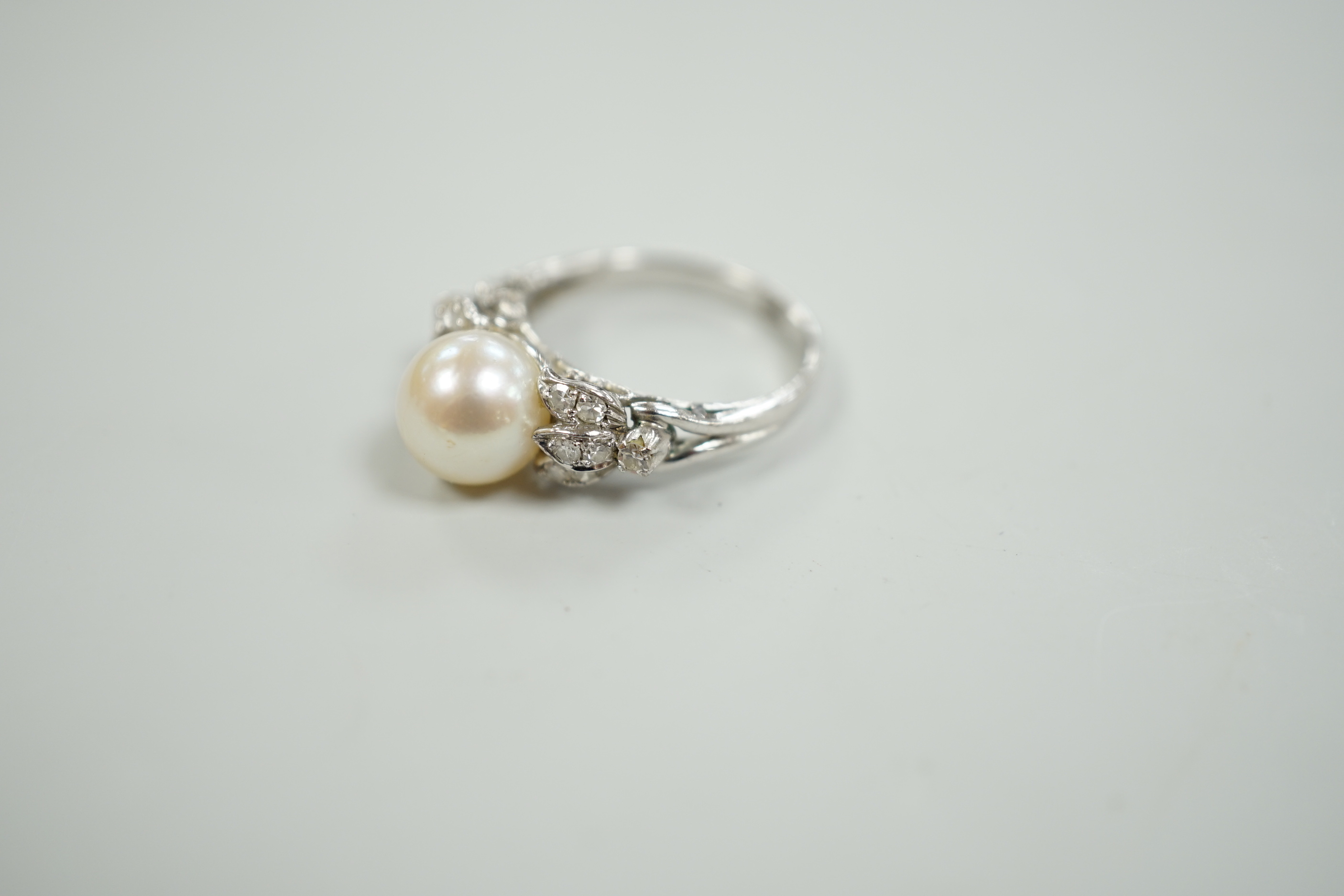 A 14k white metal and single stone cultured pearl set dress ring, with diamond cluster set shoulders, size J, gross weight 3.4 grams.